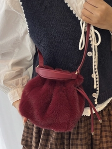 Sac seau rouge en peluche avec bandoulière en cuir porté par un mannequin pour l'automne