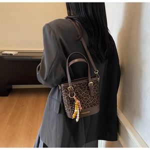 Detail of a brown leopard print bucket bag with beaded charm and adjustable strap