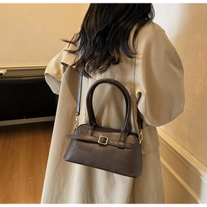 Detail of a dark brown PU leather shoulder bag styled with a beige trench coat for a chic look