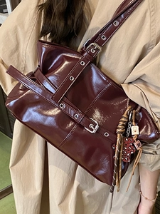 Sac plissé en cuir verni bordeaux avec œillets argentés et breloque ours élégante