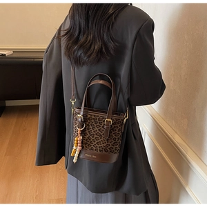 Detail of leopard print bucket bag with brown leather base and beaded charm accessory
