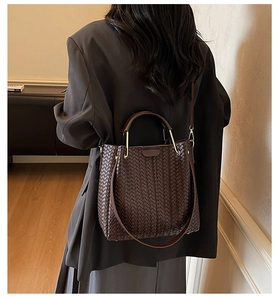 Detail of dark brown woven tote bag showing leather texture and metal handle