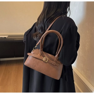 Detailed view of brown faux leather shoulder bag with gold buckle and adjustable strap