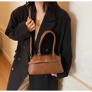 Detail of vintage brown leather bag with golden buckle and adjustable strap on a model