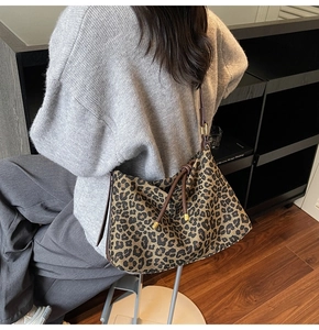 Detail of leopard print tote bag with brown leather strap and golden metal hardware