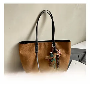 Close-up of brown suede tote bag with rhombus patterns and a cute bear charm accessory