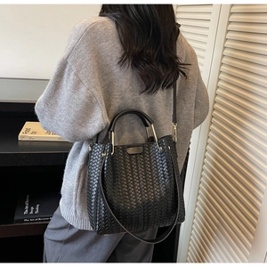 Model view of a black woven bucket bag with gold ring handles for daily commuting