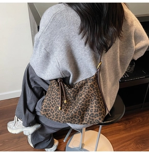 Detail of leopard print tote featuring drawstring accents and gold metal tips