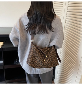 Detail view of stylish leopard print tote bag with brown straps on model's shoulder