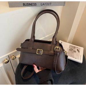 Detailed close-up of brown faux leather texture and golden buckle on women shoulder bag