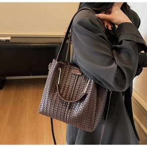 Model shot of a dark brown woven leather bucket bag featuring detailed texture and strap