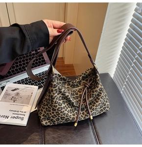 Detail of leopard print tote bag featuring leather tassel and secure zipper closure