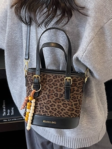 Fashionable leopard print bucket bag with wooden bead charm and golden hardware detail