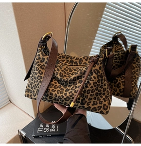 Detail view of leopard print tote bag with brown leather straps and gold metal hardware
