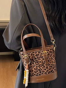 Chic leopard print bucket bag with brown leather trim and beaded charm for women