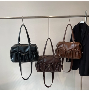 Detail view of large pleated tote bags in black, dark brown, and caramel synthetic leather