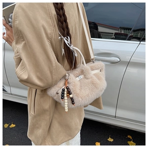 Detailed macro view of soft beige plush faux fur bucket bag with wooden bead charm