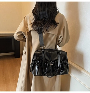Model wearing a black pleated faux leather tote bag with stylish shoulder strap details