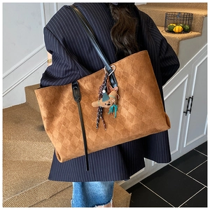 Detail of dark brown tote bag with quilted texture, suede finish and bear charm