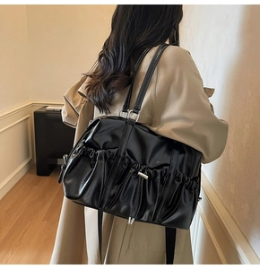 Detail of large black pleated tote bag with silver hardware on a model's shoulder
