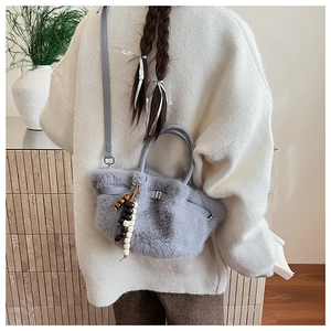 Detail of grey plush faux fur bucket bag with wooden bead charm and leather handle