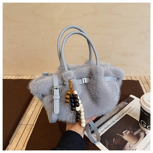 Detail of plush grey faux fur handbag featuring a wooden bead tassel and soft texture
