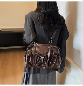 Close-up of pleated side pockets and glossy PU leather texture on brown tote bag