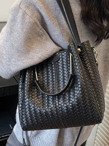 Minimalist black woven leather bucket bag with top handle and adjustable shoulder strap