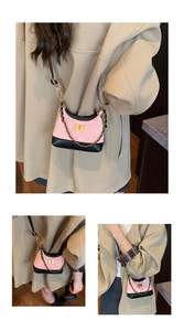 Detail view of pink and black quilted crossbody bag with golden twist lock and metal chain
