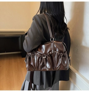 Detailed shot of dark brown polished leather bag featuring pleated drawstring accents