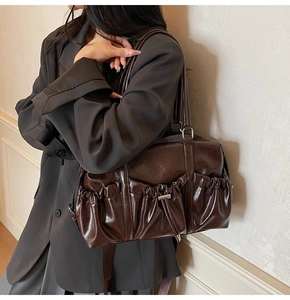 Detailed view of the dark brown pleated tote bag featuring drawstring side pocket design