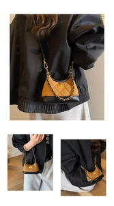 Close-up of retro suede crossbody bag with gold chain strap and quilted details