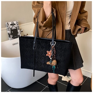 Detailed view of large black tote bag with quilted suede texture and cute star charms