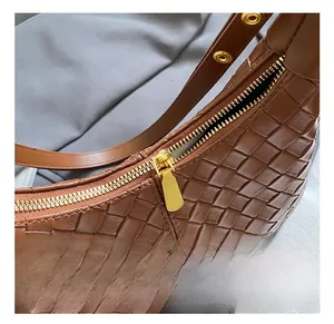 Detail shot of brown woven leather texture and polished golden metal zipper on bag
