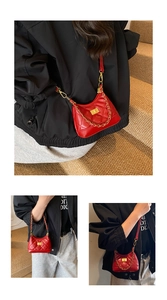 Close-up of red quilted suede crossbody bag with gold chain strap and turn-lock closure
