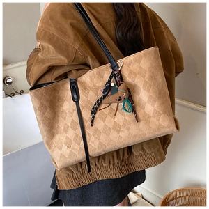 Detailed close-up of khaki tote bag with diamond lattice pattern and cute bear charm