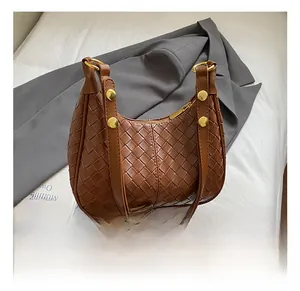 Detailed view of the woven brown crescent bag featuring gold hardware and leather texture