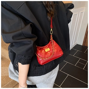 Detailed view of a red quilted crossbody bag with a chunky gold chain strap for women