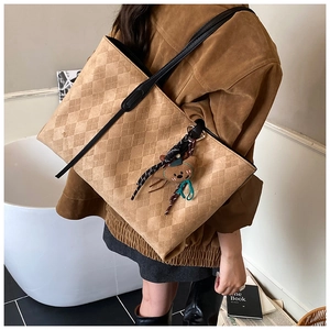 Close-up of brown quilted tote bag with bear charm detail for professional commuting style