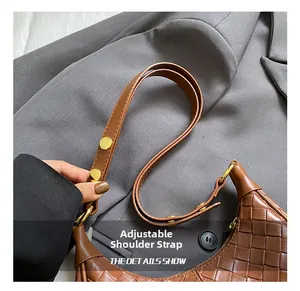 Detail of adjustable leather shoulder strap with gold metal buckle on woven bag