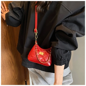 Model wearing a red quilted square crossbody bag with gold turn-lock and chain detail