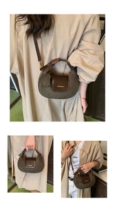 Detail of retro crescent bag in brown and green suede with a heart-shaped charm