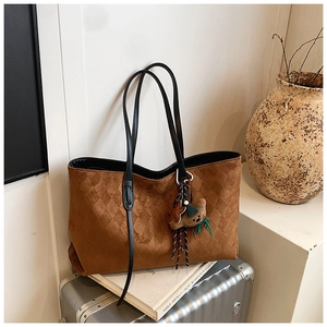 Detail of dark brown tote bag with rhombic embossed suede and bear charm pendant