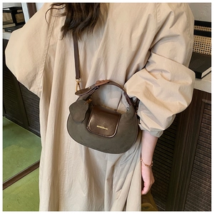 Detail view of the olive green and brown leather crescent crossbody bag worn by a model