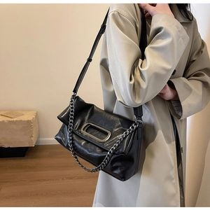 Close-up of black crossbody bag featuring textured faux leather and a chunky silver chain