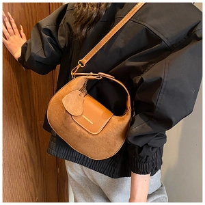 Detail of vintage brown crescent bag with suede patchwork and heart pendant accessory