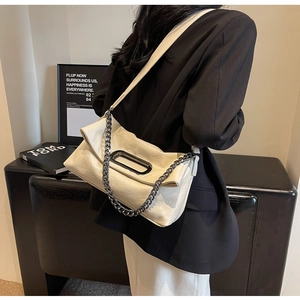 Close-up of cream glossy leather shoulder bag with metal chain strap and unique handle