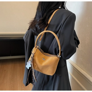 Detail view of mustard yellow vintage bucket bag with elegant ribbon and bear charm