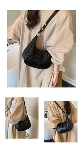 Detail of black woven crescent bag featuring gold metal rings and premium textured leather