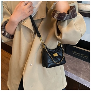 Close-up of black quilted crossbody bag with gold metallic lock and chain strap detail